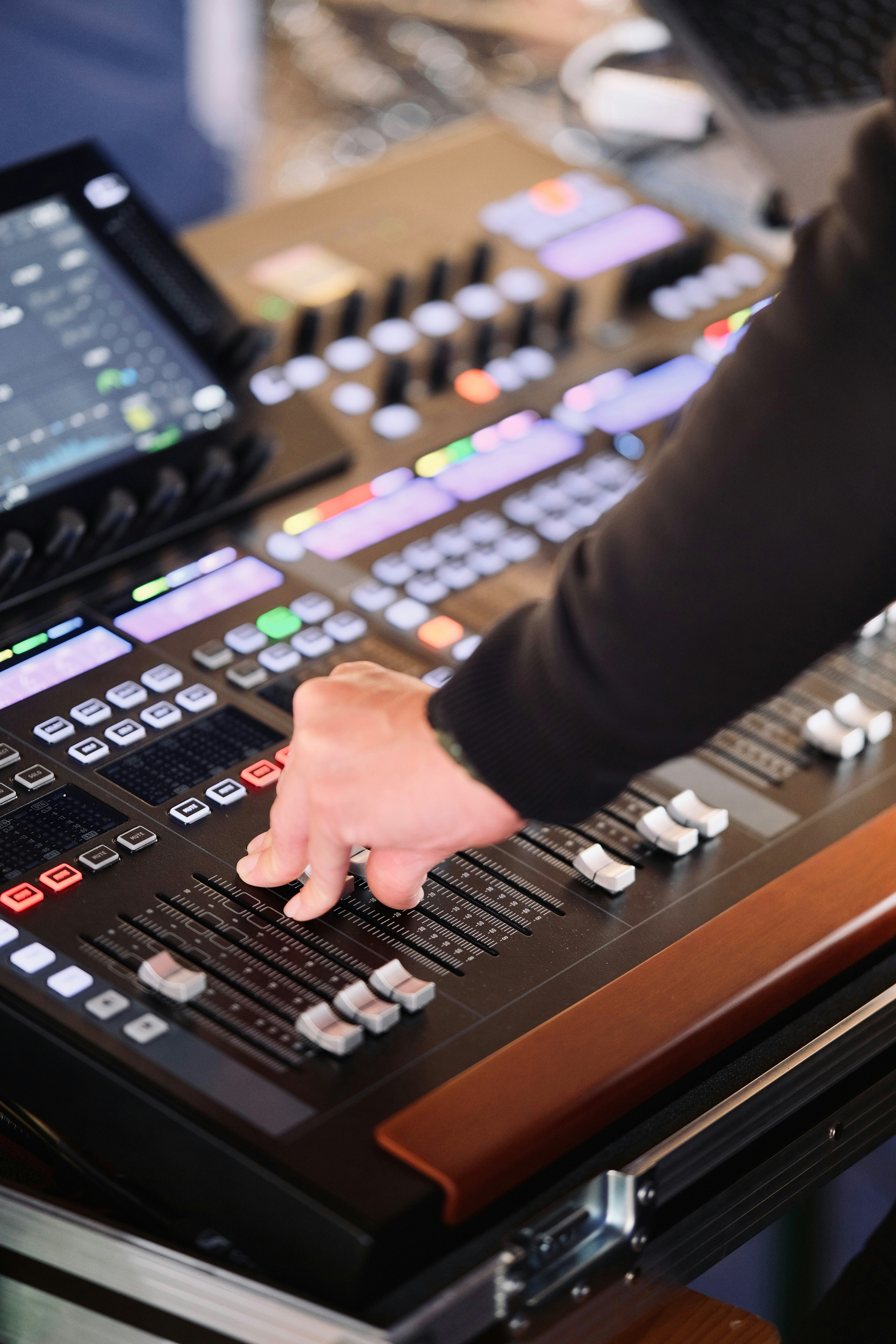 Hand adjusting faders on an audio mixing console